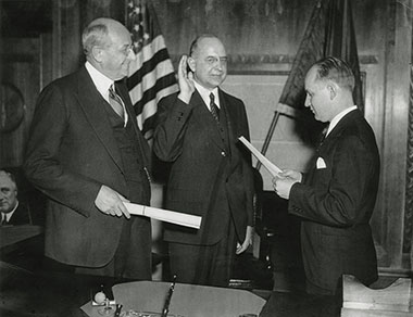 Ugo Carusi (right), executive assistant to Attorney General Homer Cummings, administers the oath of office to Stanley F. Reed (center) on March 25, 1935.  Attorney General Cummings looks on as he holds Reed’s commission.  As Solicitor General from March 1935 to January 1938, Reed once argued six cases during a two-week period.