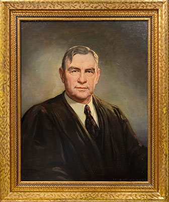 Bust-length portrait of Chief Justice Harlan Fiske Stone by Henry Salem Hubbell, circa 1942. Chief Justice Stone is shown in three-quarter right profile, with his head turned towards the viewer. He is depicted wearing a black judicial robe over a white shirt with a turned-down collar and a black tie featuring a red and gray geometric design.