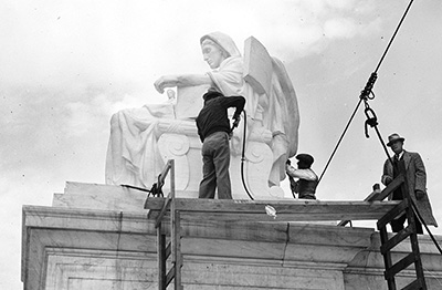 Carvers add finishing touches to Contemplation of Justice, as sculptor James Fraser looks on, November 1935.