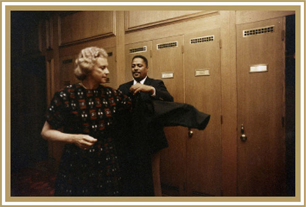 Messenger Tim Moore assists Justice Sandra Day O'Connor with her robe in the Justices' Robing Room, c. 1986.